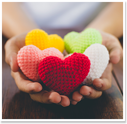 Student hands holding heart-shaped made of yarn